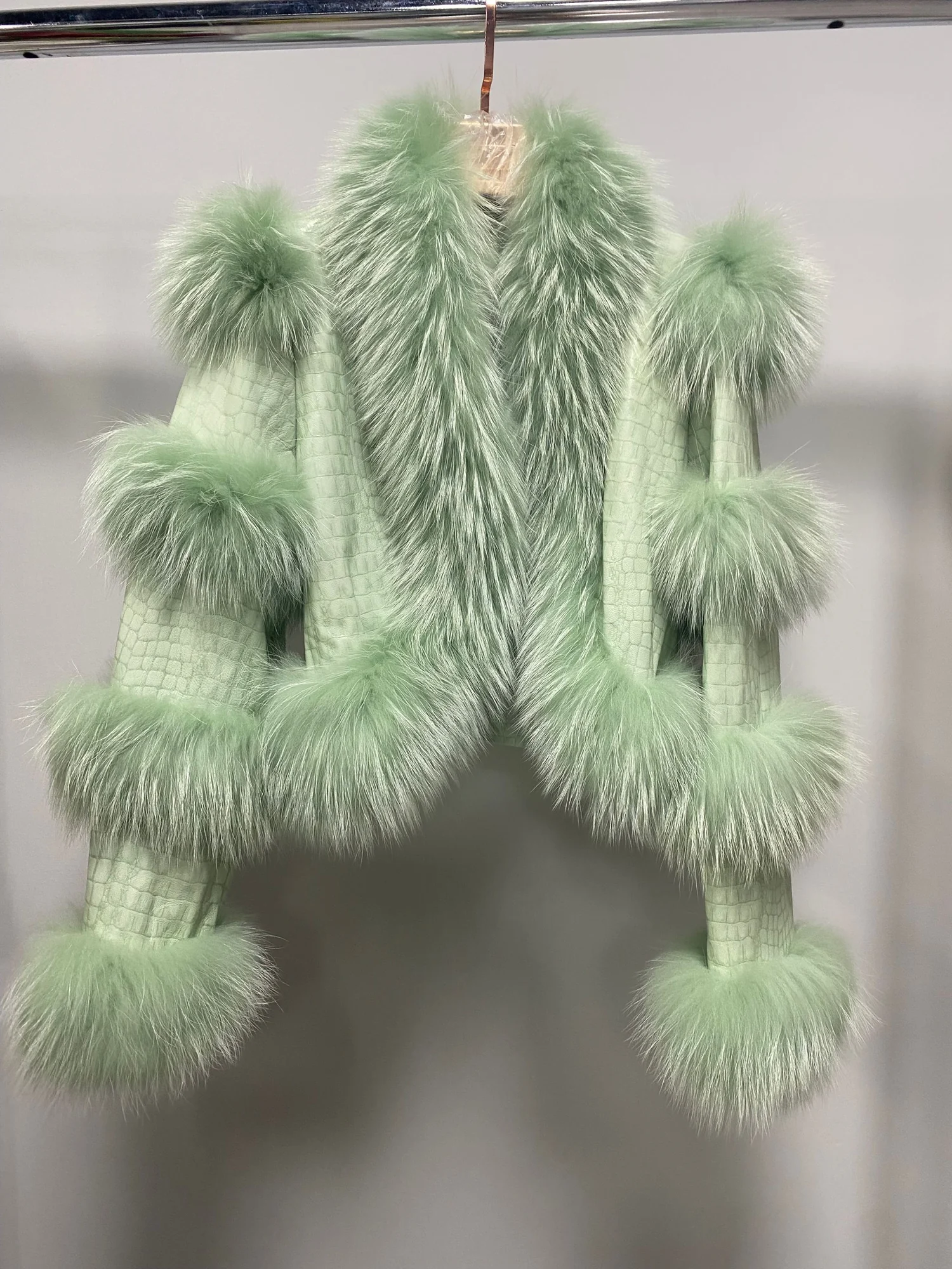 Light green leather jacket front view with raccoon-fur trim and sleeve bands
